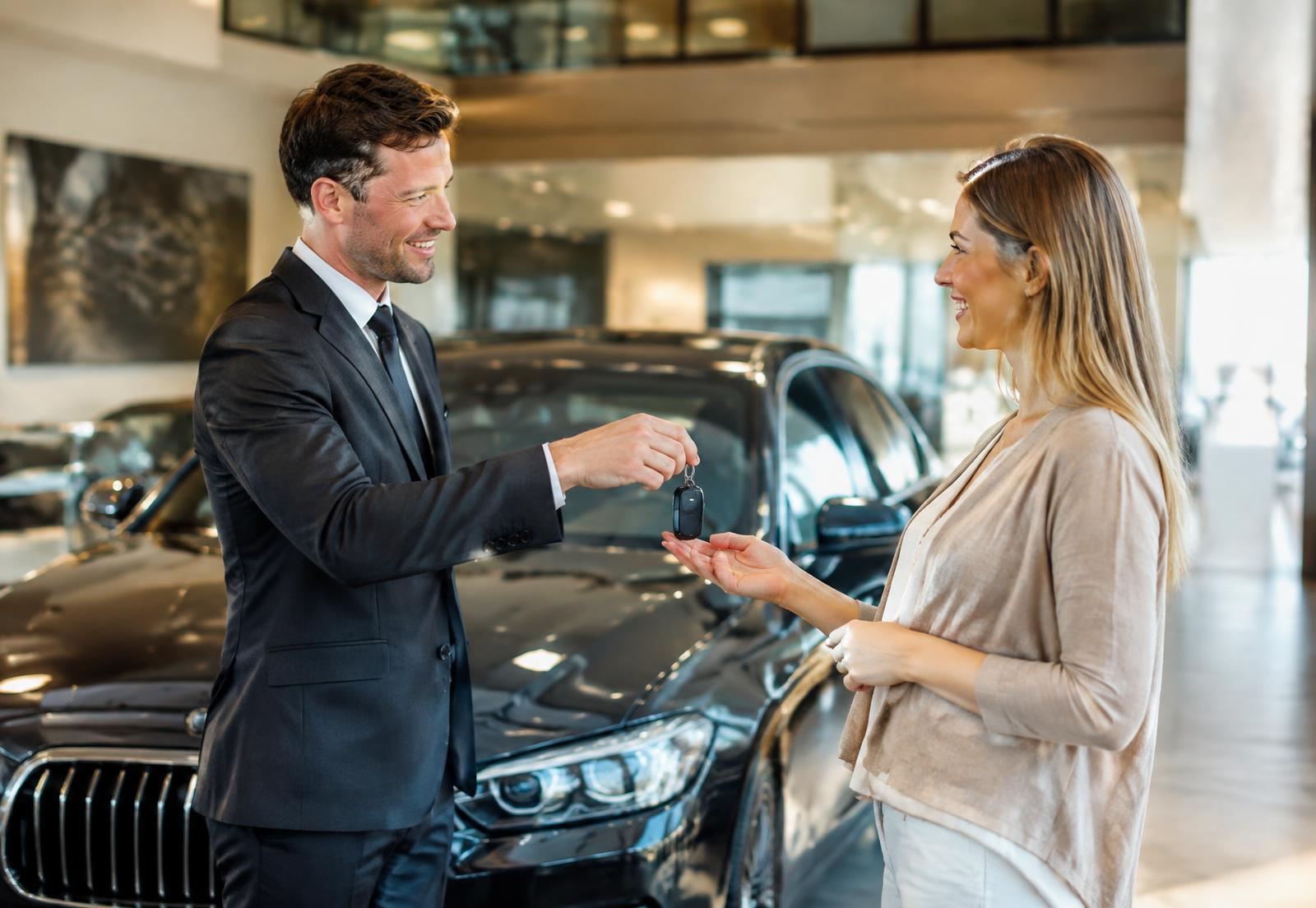 Salesman handing car keys to a happy new customer
